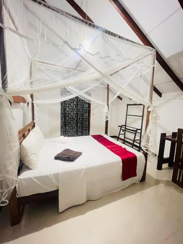 a bedroom with a white canopy bed and a chair at Sigiri Holiday Bungalow in Sigiriya