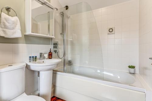 y baño con lavabo, aseo y bañera. en Merlin House at Lower Mill Estate A gorgeous home with lake access, air conditioning and luxury spa access, en Somerford Keynes