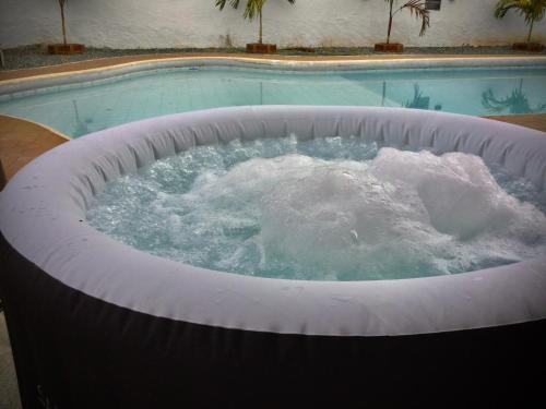 a large hot tub in front of a swimming pool at Magiko Suites in Roldanillo