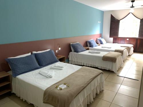 a hotel room with three beds in a room at Pousada Moça Bonita in Ubatuba
