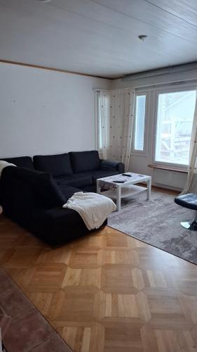 Una sala de estar con un sofá negro y una mesa. en Omakotitalo, en Sodankylä