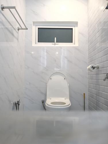 a white bathroom with a toilet and a window at H62 Muar Home in Muar