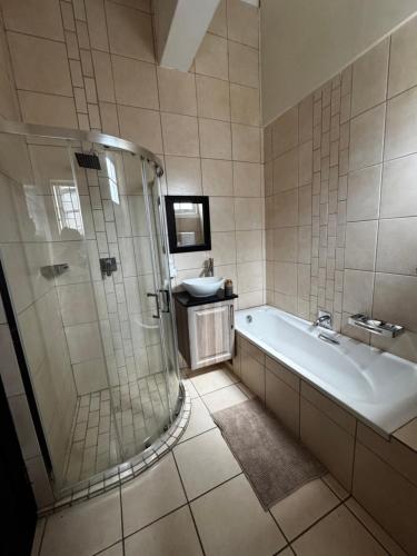 un bagno con vasca, doccia e lavandino di Dior-X Manor a Durban