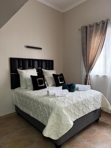 una camera da letto con un grande letto con cuscini bianchi e neri di Dior-X Manor a Durban
