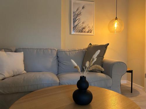 a living room with a couch and a vase on a table at Traumhafte Ferienwohnung zwischen Ostsee und Hansestadt in Stockelsdorf