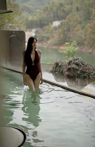 a woman in a bathing suit standing in the water at Yakamoz Qianchuan Hotel in Lin'an