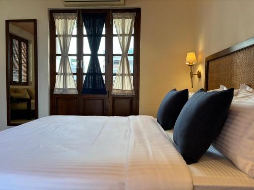 a bedroom with a large white bed with blue pillows at Charme de Pondicherry by stayxp in Puducherry
