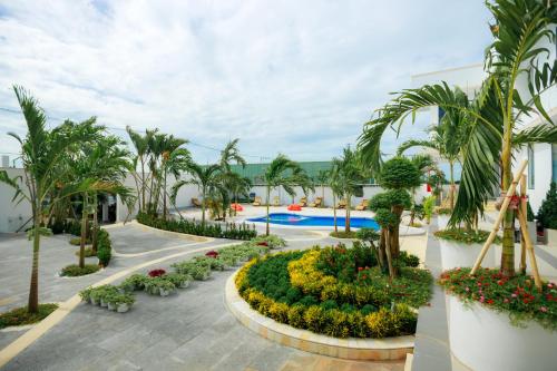 a resort with a pool and palm trees and flowers at Tuong Vy Mini Bay Hotel Mui Ne in Ấp Ngọc Hải