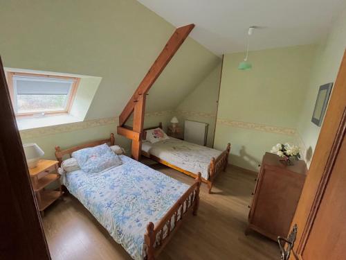 a attic bedroom with two beds and a window at Maison à la campagne gîte in La Motte-Fouquet