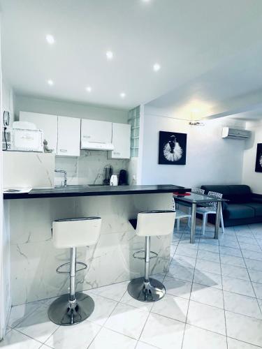 une cuisine avec un comptoir et deux tabourets de bar dans l'établissement Grand appartement centre piéton Cannes, à Cannes