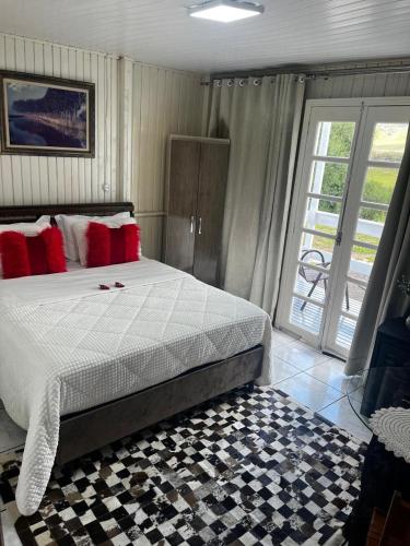 a bedroom with a large bed with red pillows at Pousada Frio da serra in Bom Jardim da Serra