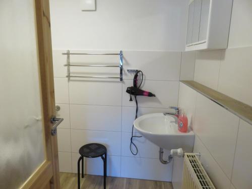 a white bathroom with a sink and a stool at Ferienhaus Diana in Thale