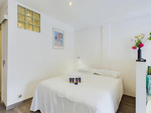 - une chambre blanche avec un lit blanc et un vase avec des fleurs dans l'établissement Valentina 16/18 Rue rouaze cannes, à Cannes