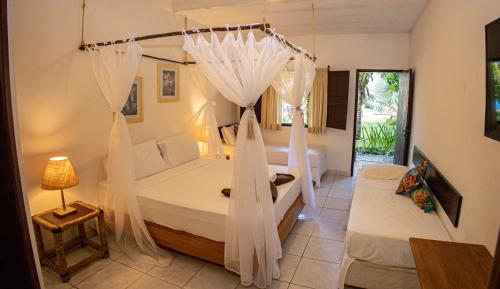 a bedroom with a bed with white mosquito netting at Pousada Saudosa Maloca in Arraial d'Ajuda