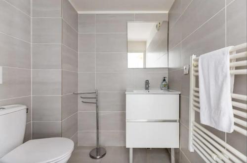 a white bathroom with a toilet and a sink at L'Escapade Paris in Le Kremlin-Bicêtre