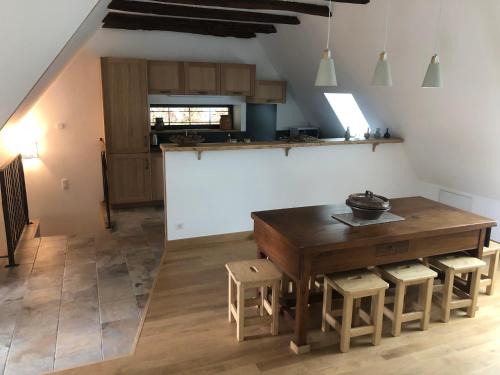 - une cuisine avec une table et des tabourets en bois dans l'établissement Grange Gaïa sur Rivière, à Taussac