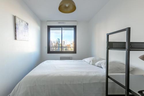 a white bedroom with a bunk bed and a window at L'Escapade Paris in Le Kremlin-Bicêtre