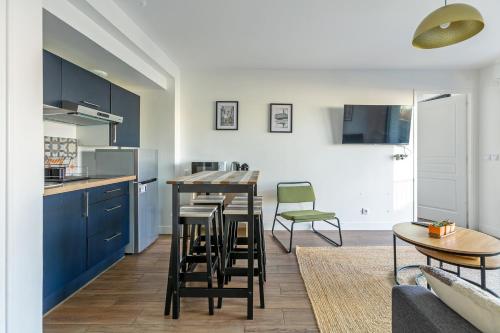 a kitchen with blue cabinets and a table and chairs at L'Escapade Paris in Le Kremlin-Bicêtre