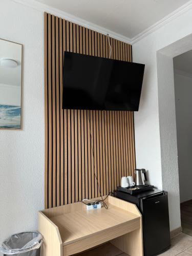 a room with a table and a television on a wall at Hotel Nordseegruß in Norddeich