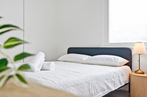 a bedroom with a bed with white sheets and a plant at Urban Stay Central Convenience on Broadway Ultimo in Sydney