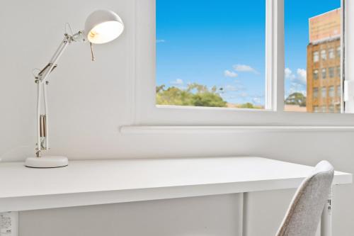 a desk with a lamp and a chair in front of a window at Urban Stay Central Convenience on Broadway Ultimo in Sydney