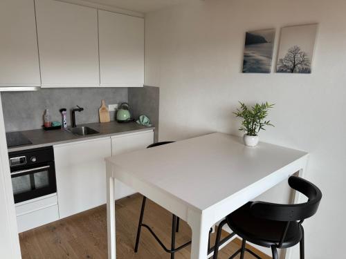 a kitchen with a white table and two black chairs at Eva's Seeblick in Krattigen