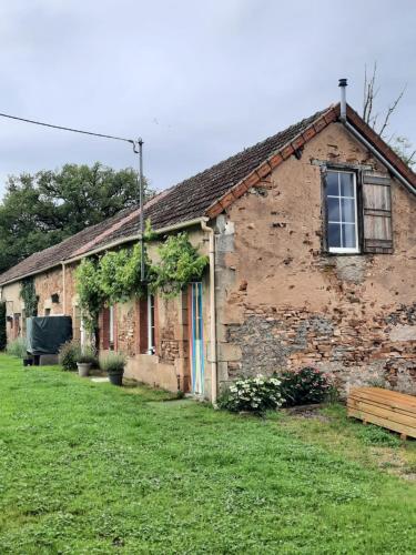 an old brick building with a window and green grass at Gîte 'La BelleVue' in Feusines