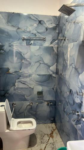 a bathroom with a toilet and a blue tiled wall at OYO Hotel Paradise in Orchha