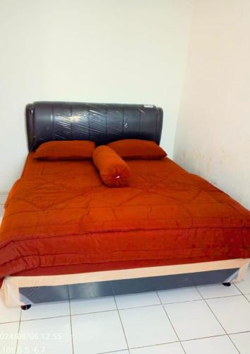a bed with an orange comforter and two pillows at Kebun Teduh Sukaharja Cijeruk Bogor in Palasari
