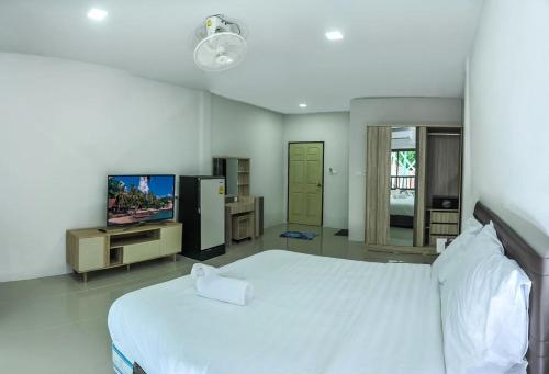 a bedroom with a large white bed and a tv at Noza INN in Khao Lak