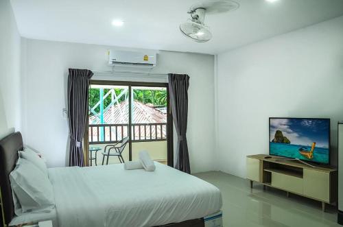 a bedroom with a bed and a tv and a window at Noza INN in Khao Lak