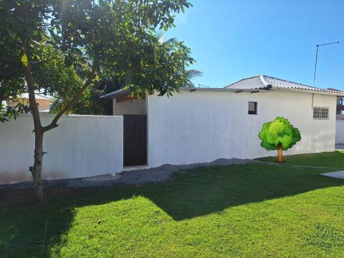 una casa bianca con un albero nel cortile di Bangalô MAR & SOL a Saquarema