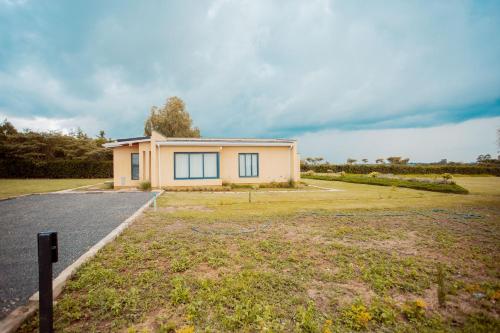 a house in a field next to a road at Phelgone Nanyuki in Nanyuki