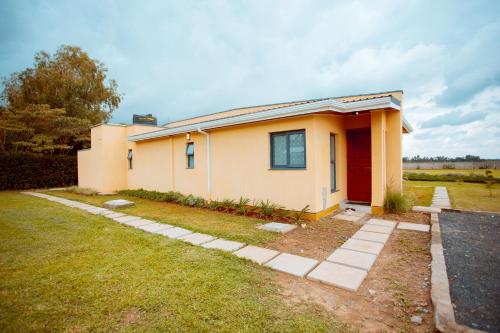 a small yellow house with a red door at Phelgone Nanyuki in Nanyuki