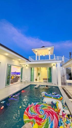 a swimming pool with a pool noodle in front of a house at Fin Camping & Pool Villa in Ban Hup Kaphong