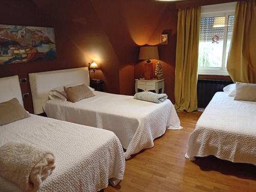 una camera da letto con due letti con lenzuola bianche e una finestra di Casa Ana a Redondela