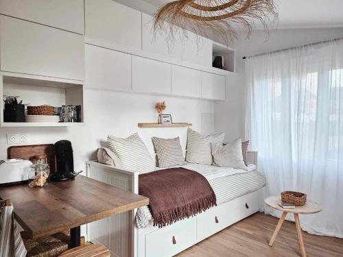 a bedroom with a bed with white walls and a table at Studio Le Petit Sablé in Concarneau