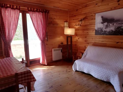 une chambre avec un lit dans une cabane en rondins dans l'établissement La Cabane d'Oza, à Saint-Pierre-dels-Forcats