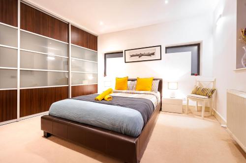 a bedroom with a large bed with yellow pillows at Bright & Modern One Bedroom Flat in Farringdon in London