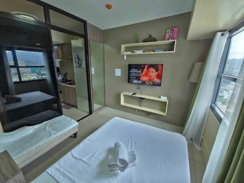 a bedroom with a white bed and a tv at Cozy Condo in the City Center at Horizons 101 in Cebu City
