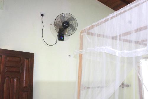 a fan hanging on a wall next to a window at Sigiriya Nature View home Stay in Sigiriya