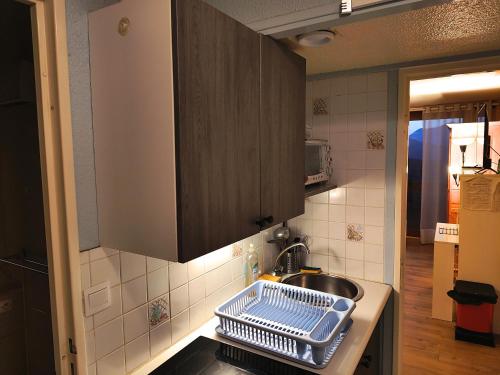 a kitchen with a sink and a dish drying rack at Résidence Au Petit Chamois in Le Corbier