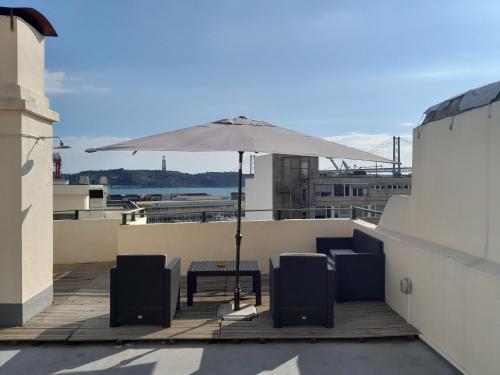 a patio with a table and an umbrella on a roof at Apartamento sobre o Rio in Lisbon