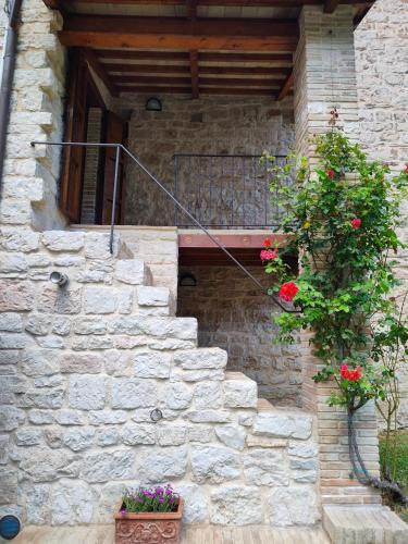 a stone building with stairs and a window and flowers at Cottege in Pietra sul Fiume in Frontone