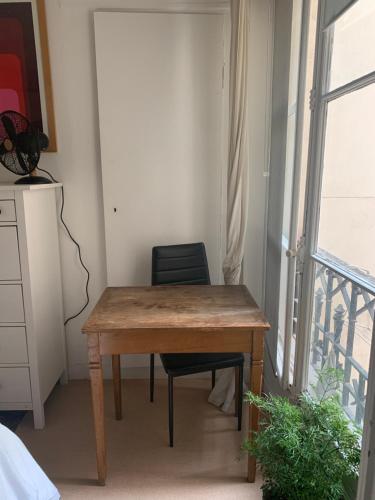une table en bois et une chaise dans une chambre avec fenêtre dans l'établissement Parisien Solitaire, à Paris