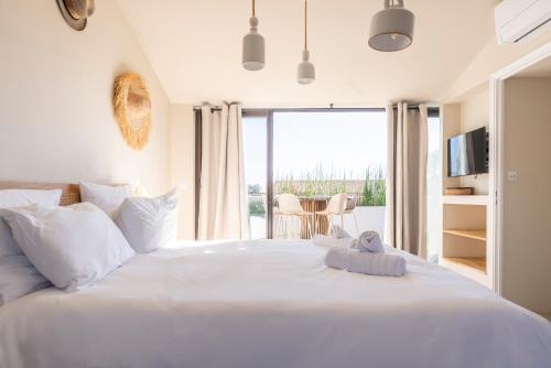 a bedroom with a large white bed with a window at Maison avec piscine et amarrage in Grimaud