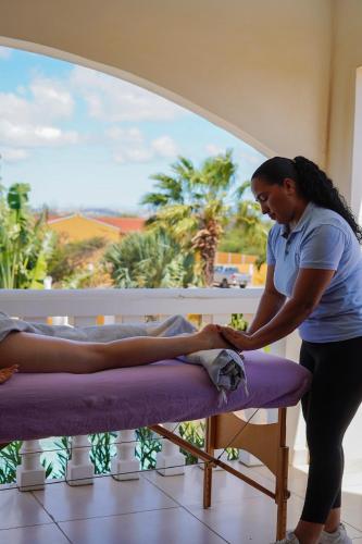 a woman is waxing a mans leg on a bed at Boutique Hotel Wanapa - Adult Friendly - 14 years and older in Kralendijk