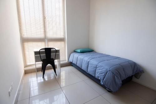 a bedroom with a bed and a chair and a window at Habitación en Providencia - Metro Salvador in Santiago