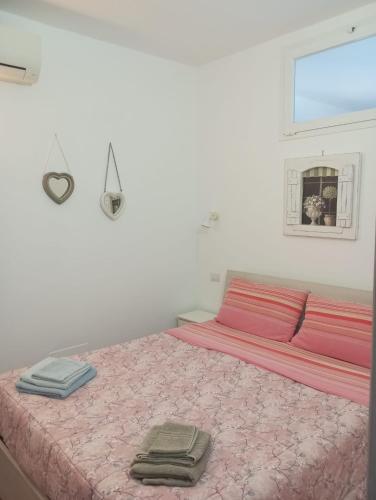 a bedroom with a pink bed with two towels on it at Tigullio Vacations in Leivi