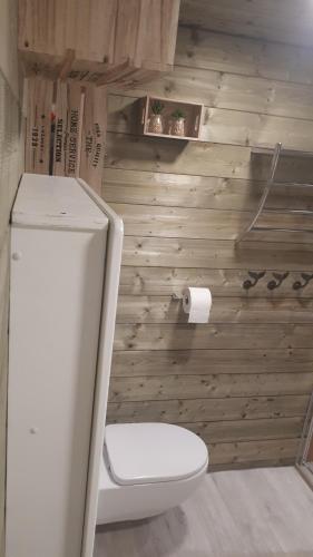 a bathroom with a toilet and a wooden wall at maison tartifume in Pornic